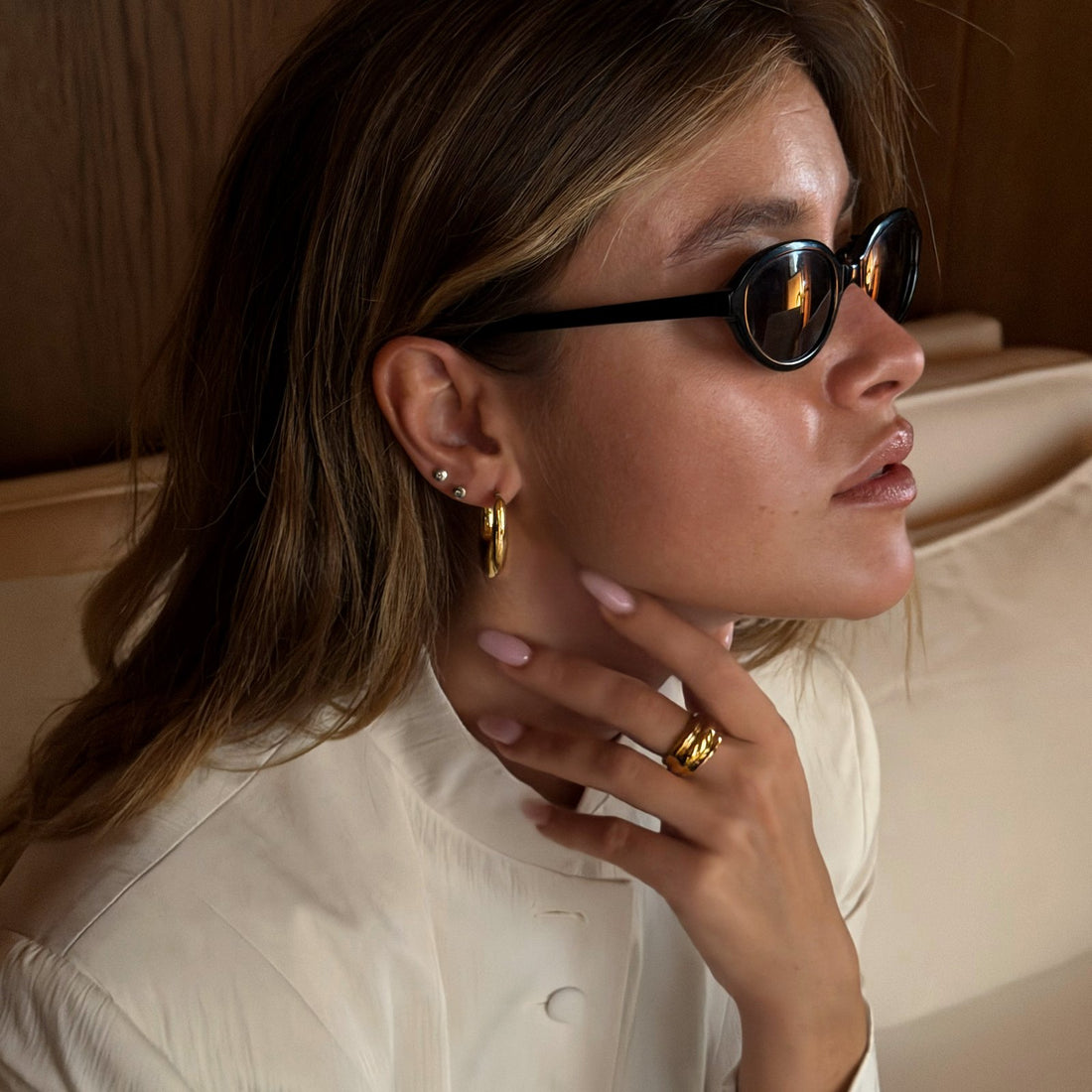 Close-up of Sasha wearing gold hoop earrings and rings